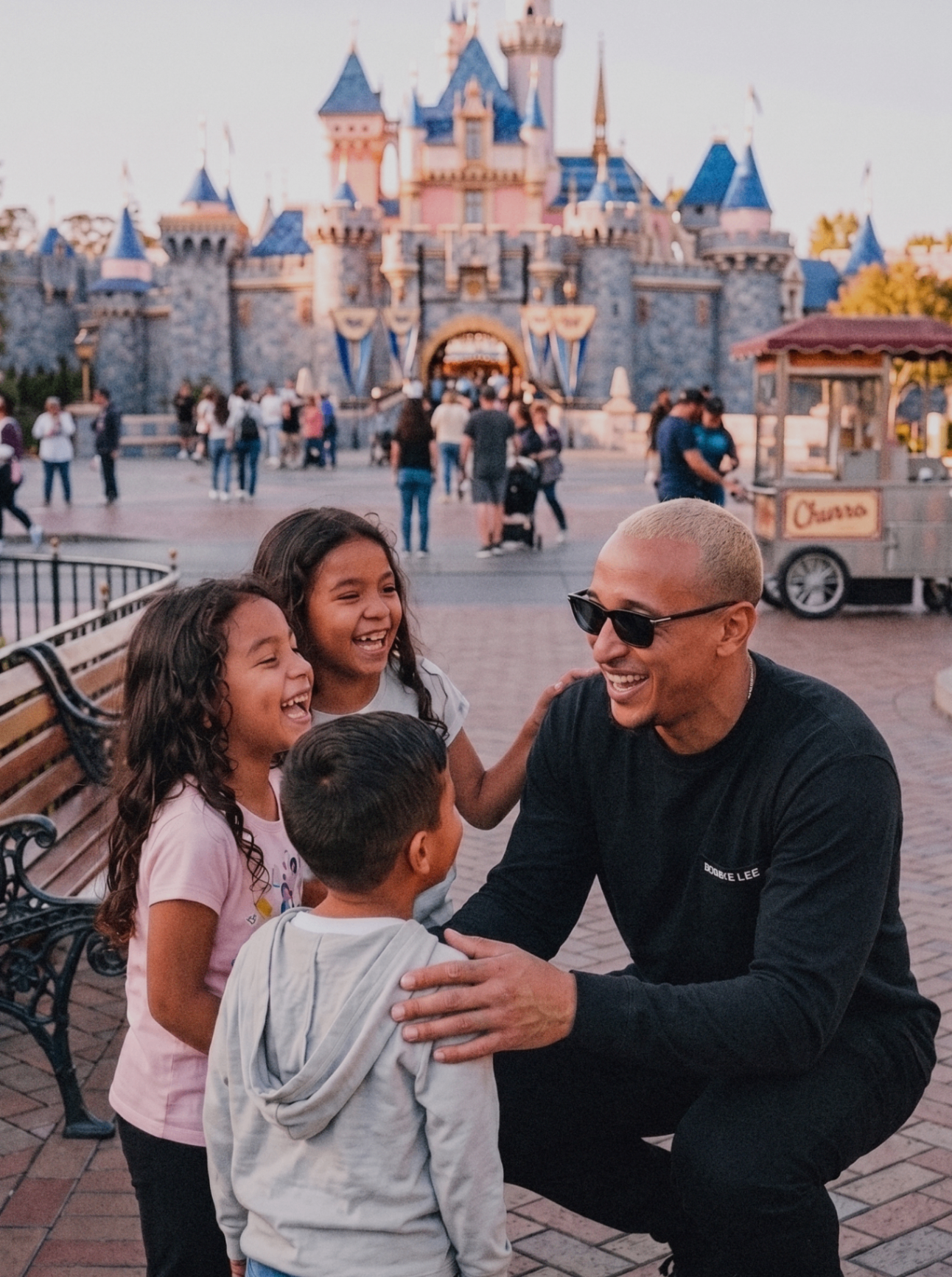 A joyful adult and three children laughing together in front of a storybook castle.
